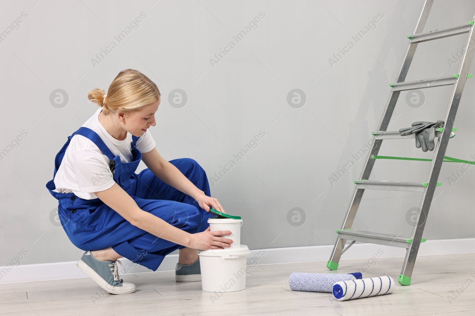 Photo of Female worker preparing to painting wall indoors