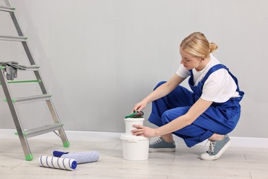 Photo of Female worker preparing to painting wall indoors