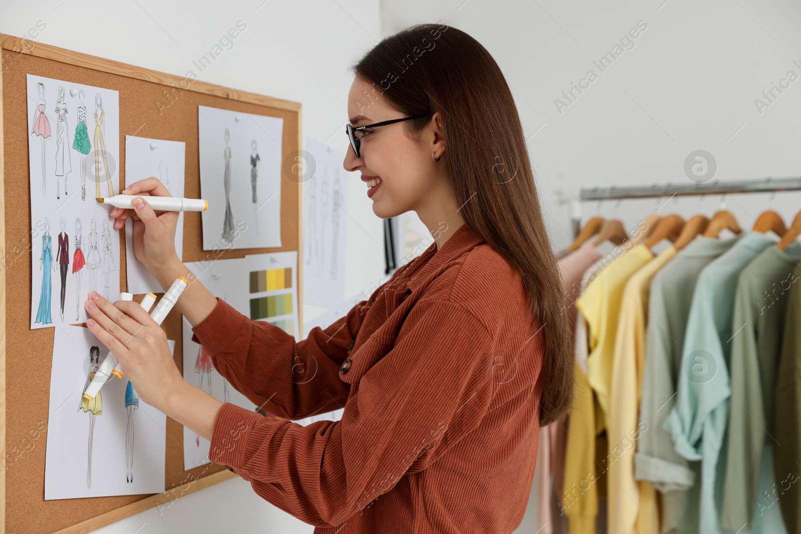 Photo of Fashion designer drawing sketch of clothes in workshop