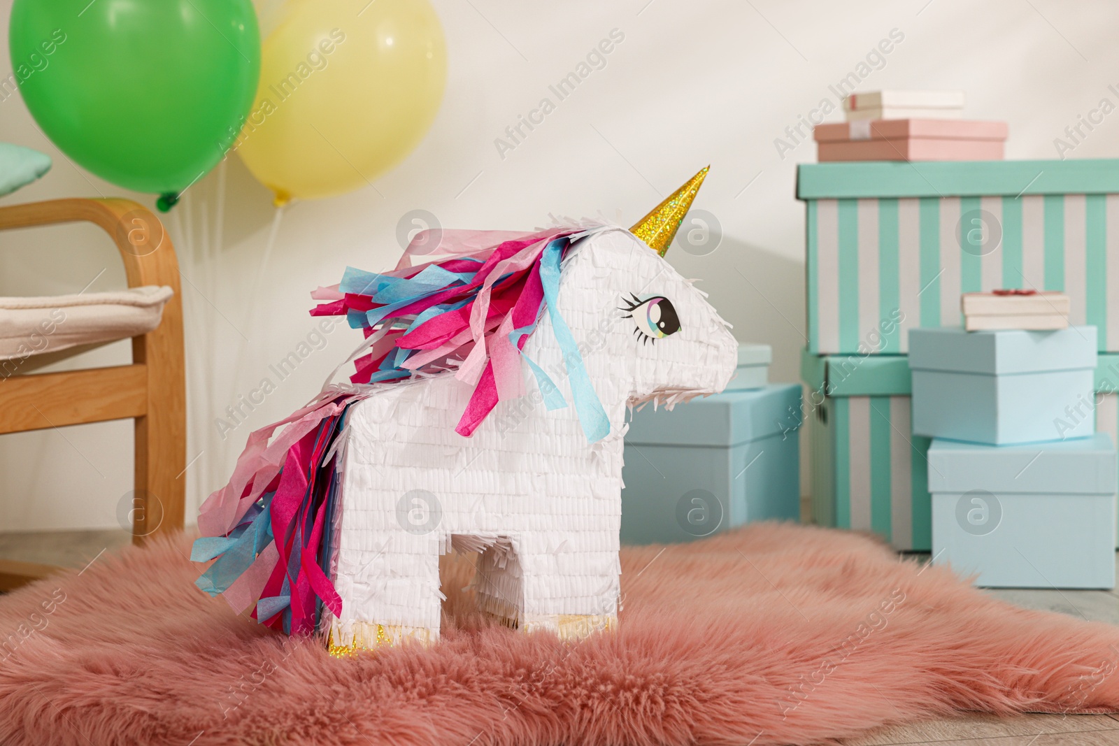 Photo of Bright pinata in shape of unicorn and party accessories in festive decorated room