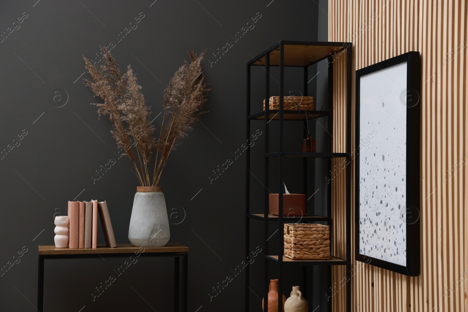 Photo of Console table with decor and shelving unit near grey wall in room. Interior design