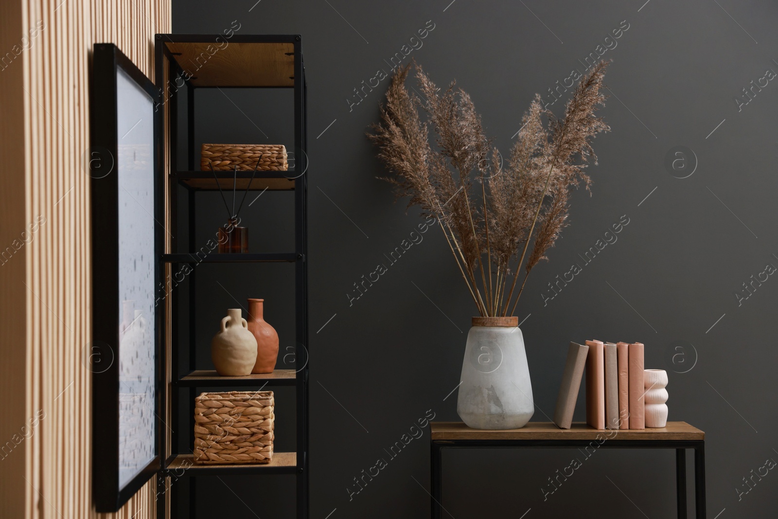 Photo of Console table with decor and shelving unit near grey wall in room. Interior design