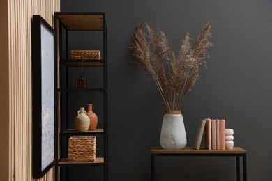 Photo of Console table with decor and shelving unit near grey wall in room. Interior design