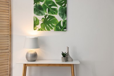 Photo of Stylish console table with lamp and decor near white wall indoors