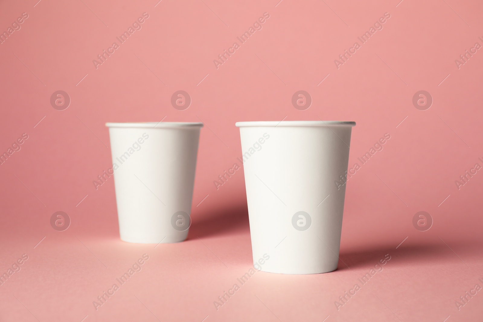 Paper cups on pink background. Mockup for design Photo of Paper cups on pink background. Mockup for design