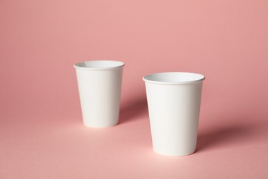 Photo of Paper cups on pink background. Mockup for design