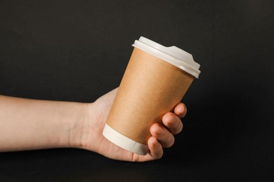Photo of Woman holding paper cup on black background, closeup. Mockup for design