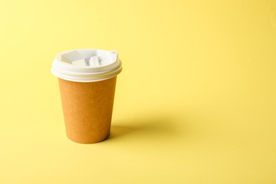 Photo of One paper cup on yellow background. Mockup for design