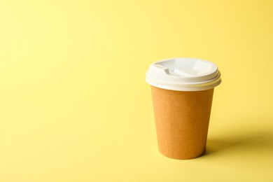 Photo of One paper cup on yellow background. Mockup for design