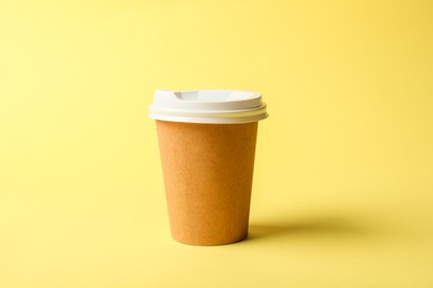 Photo of One paper cup on yellow background. Mockup for design