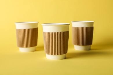 Photo of Paper cups on yellow background, selective focus. Mockup for design