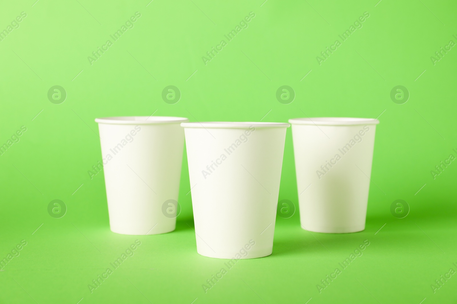 Paper cups on green background. Mockup for design Photo of Paper cups on green background. Mockup for design
