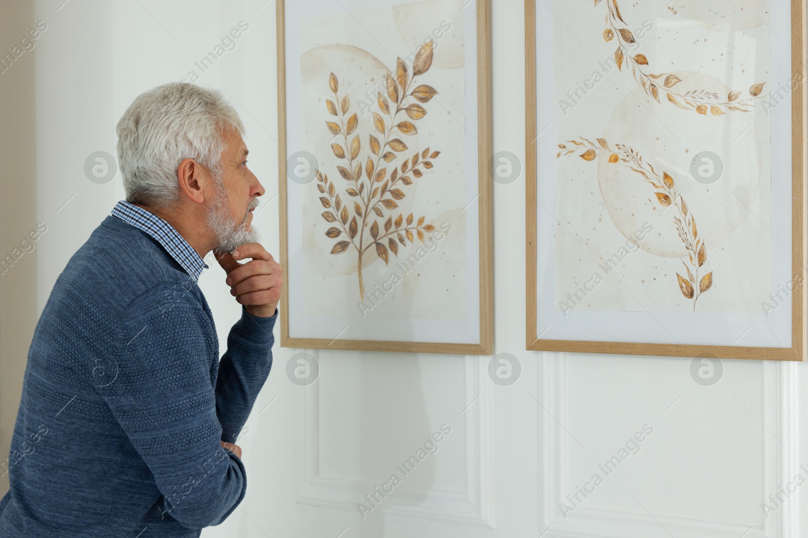 Photo of Senior man examining beautiful paintings in art gallery