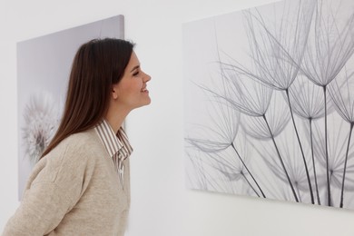 Photo of Woman examining beautiful paintings in art gallery