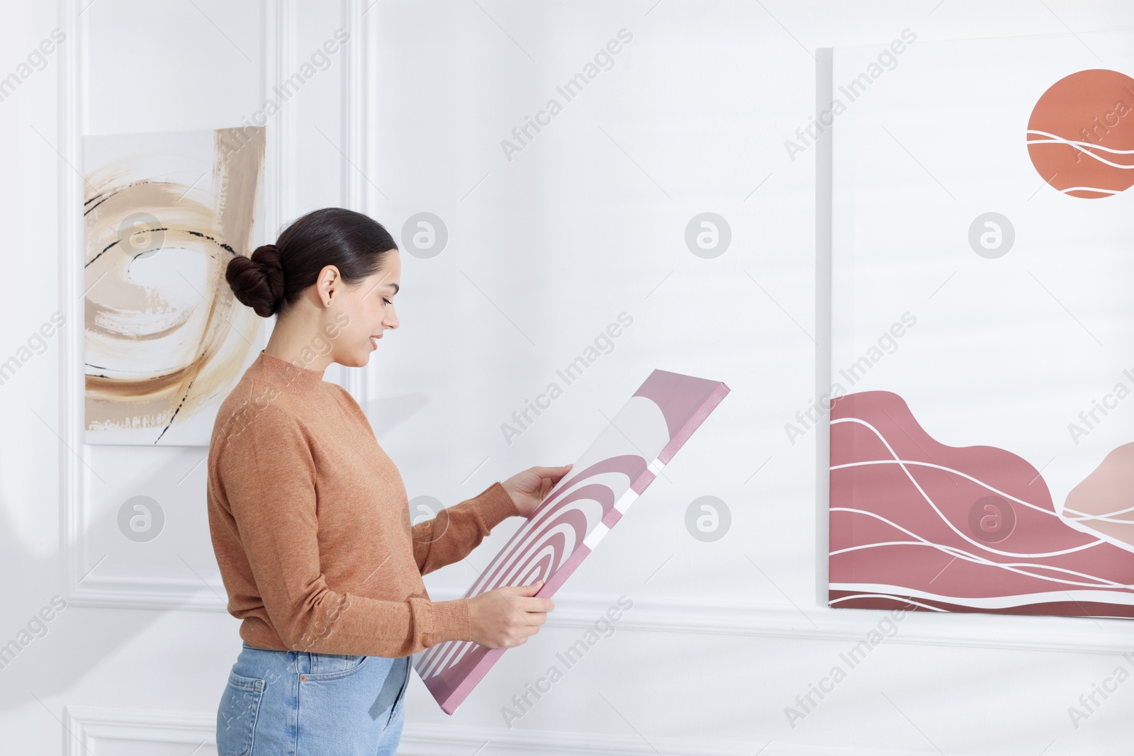 Photo of Woman hanging painting on wall in art gallery