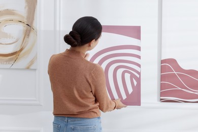 Photo of Woman hanging painting on wall in art gallery