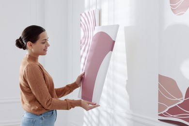 Photo of Woman hanging painting on wall in art gallery