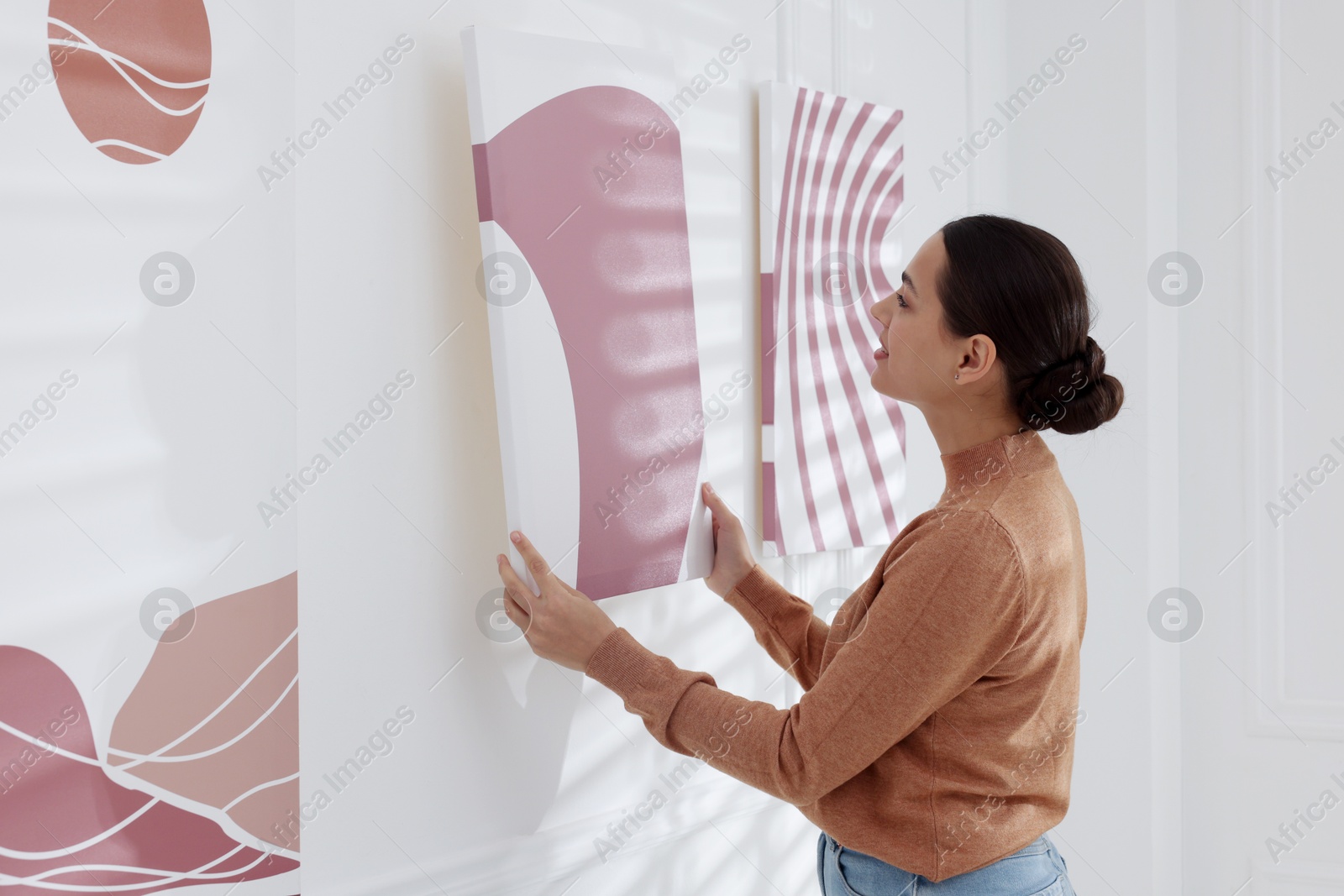 Photo of Woman hanging painting on wall in art gallery