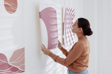 Photo of Woman hanging painting on wall in art gallery