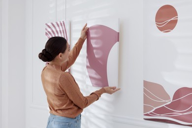 Photo of Woman hanging painting on wall in art gallery