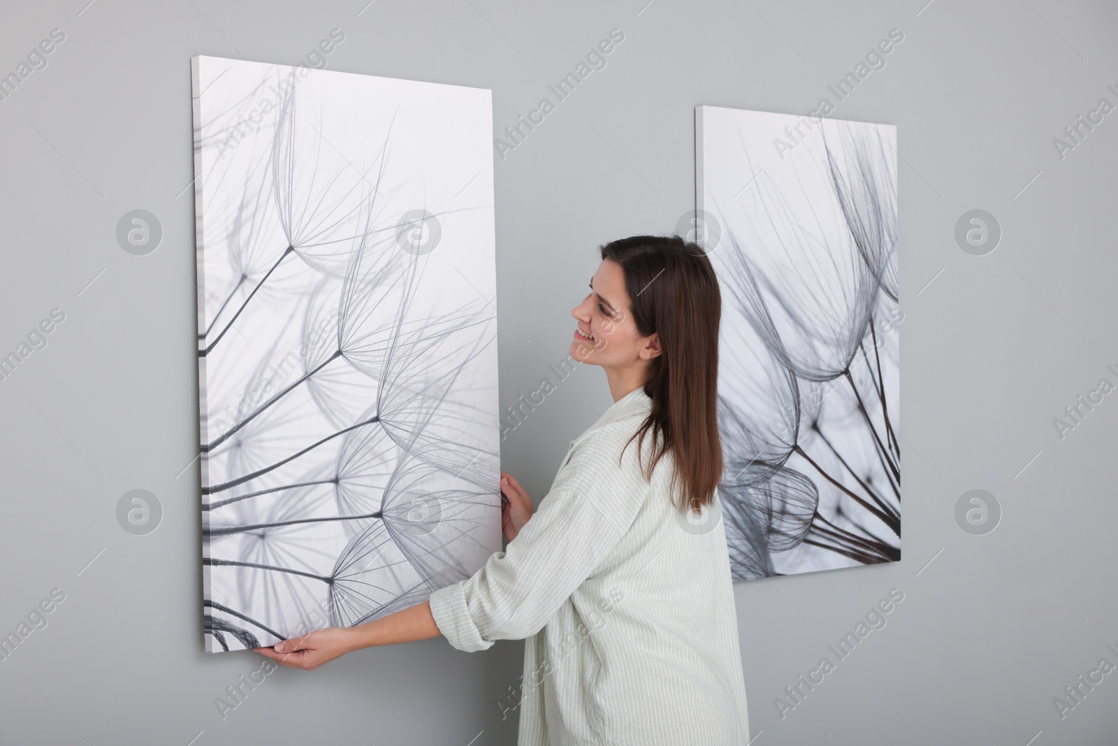 Photo of Woman hanging painting on wall in art gallery