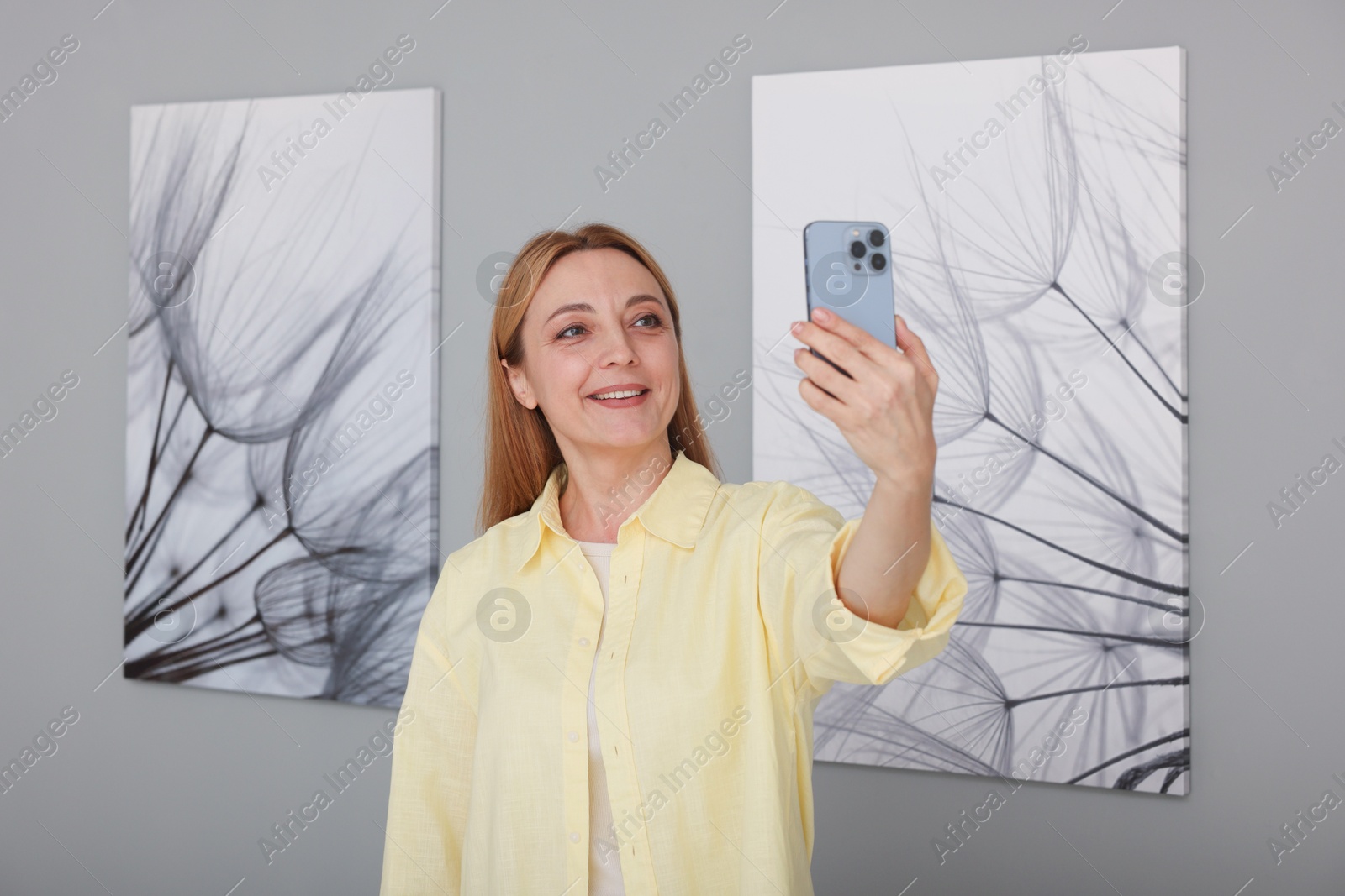 Photo of Woman taking selfie with paintings in art gallery