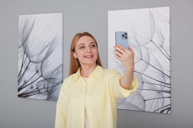 Photo of Woman taking selfie with paintings in art gallery