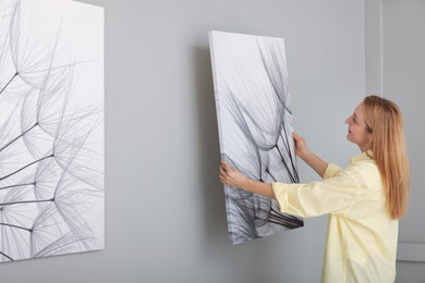 Photo of Woman hanging painting on wall in art gallery