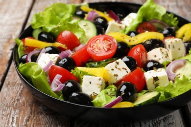 Photo of Delicious fresh Greek salad on wooden table, closeup