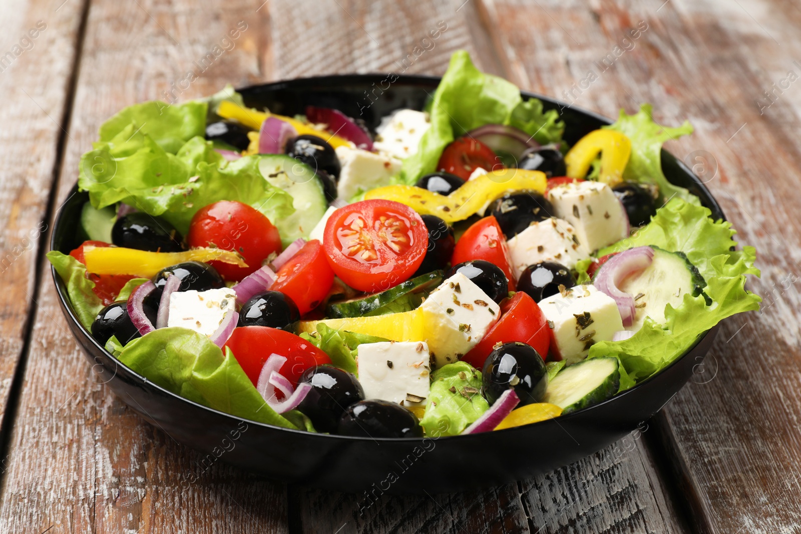 Photo of Delicious fresh Greek salad on wooden table, closeup