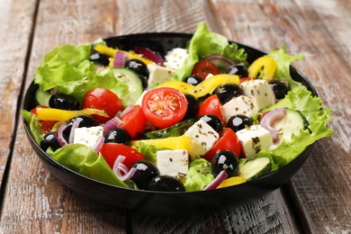 Photo of Delicious fresh Greek salad on wooden table, closeup