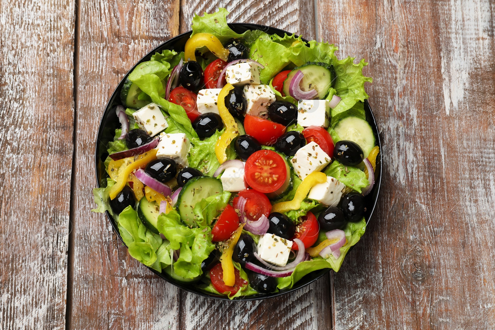 Photo of Delicious fresh Greek salad on wooden table, top view