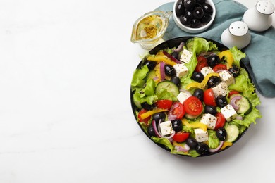 Photo of Delicious fresh Greek salad and ingredients on white table, flat lay. Space for text