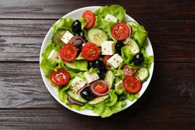 Photo of Delicious fresh Greek salad on wooden table, top view