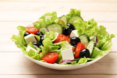 Photo of Delicious fresh Greek salad on light wooden table, closeup