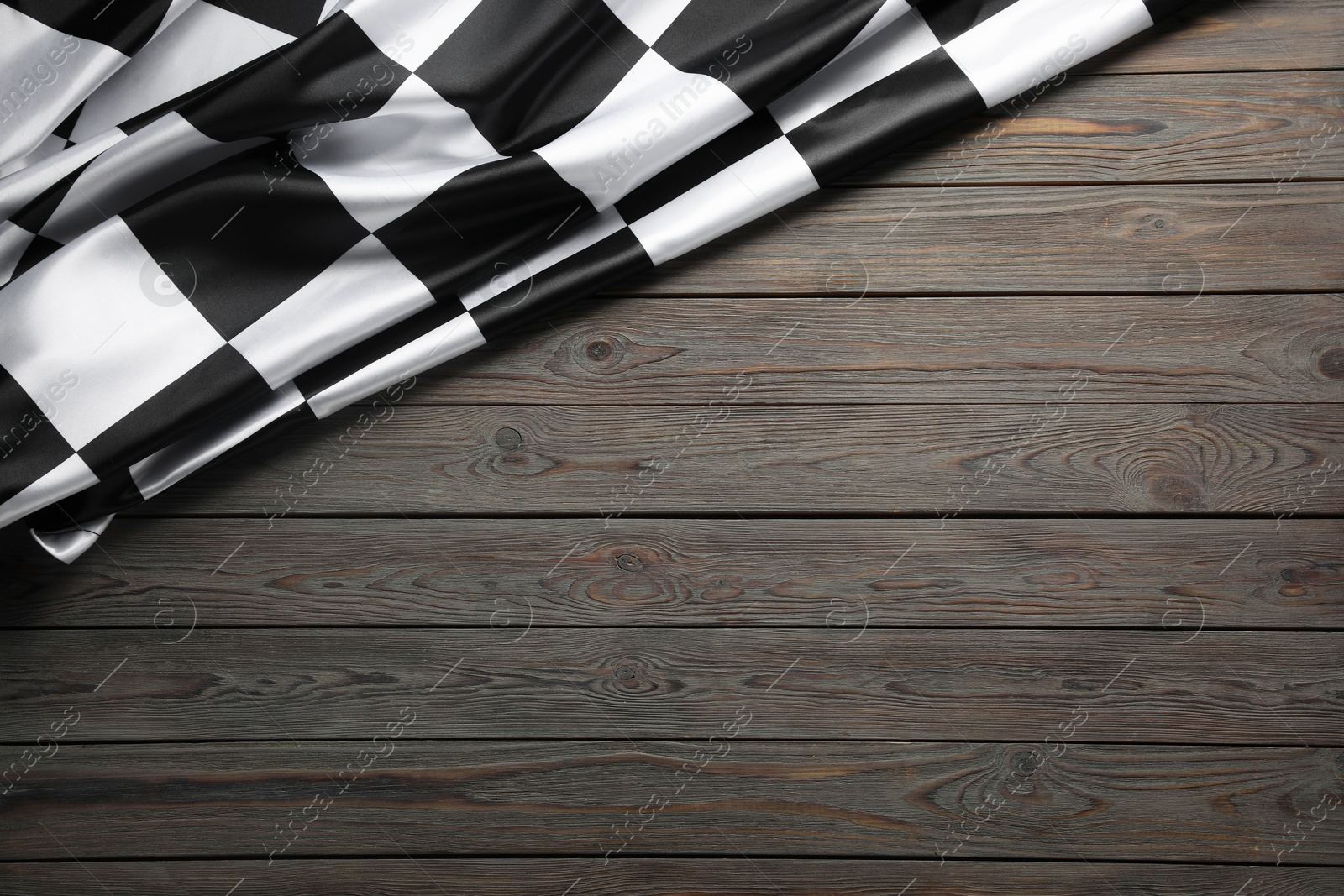 Photo of Checkered flag on wooden table, top view. Space for text