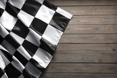 Photo of Checkered flag on wooden table, top view. Space for text