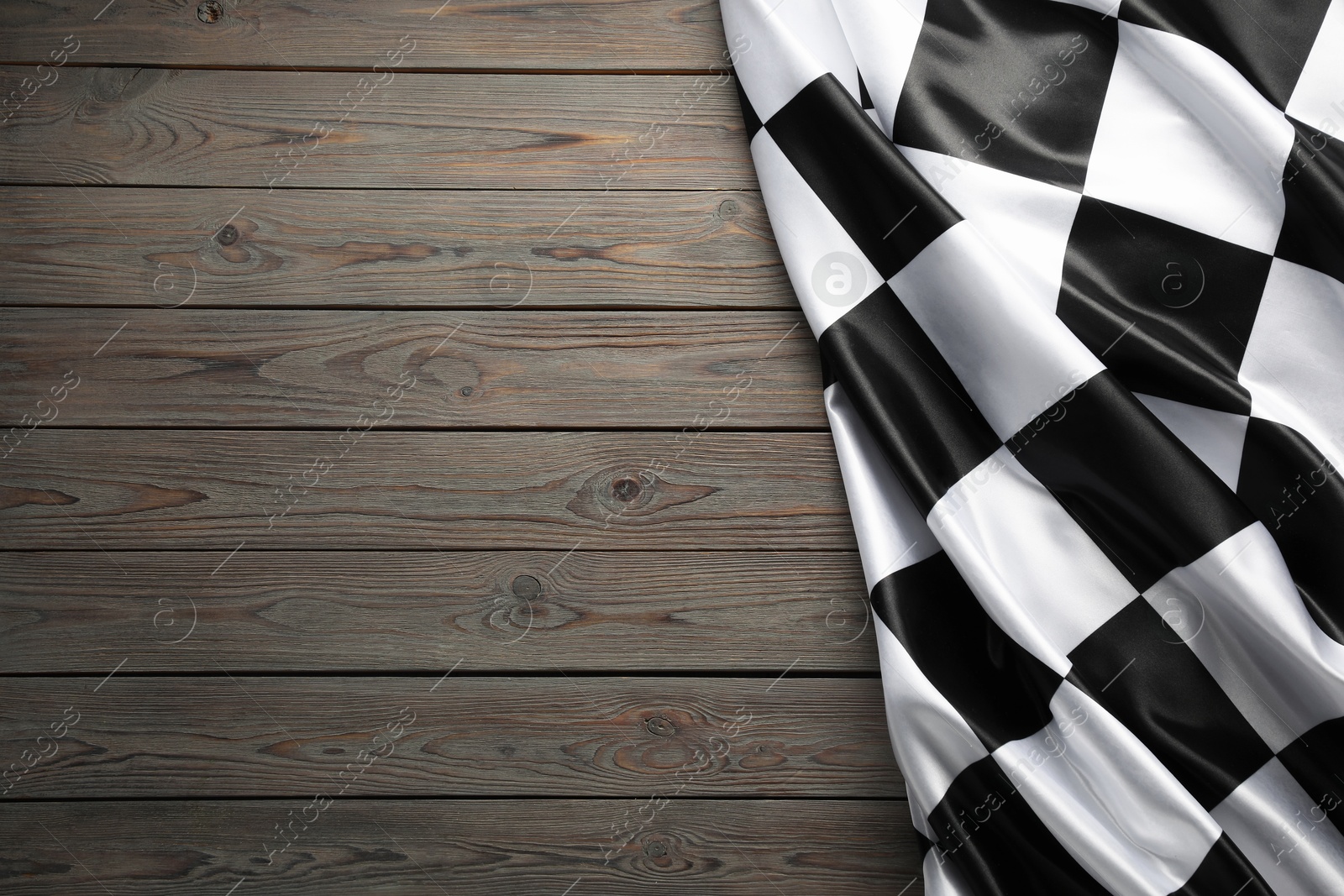 Photo of Checkered flag on wooden table, top view. Space for text