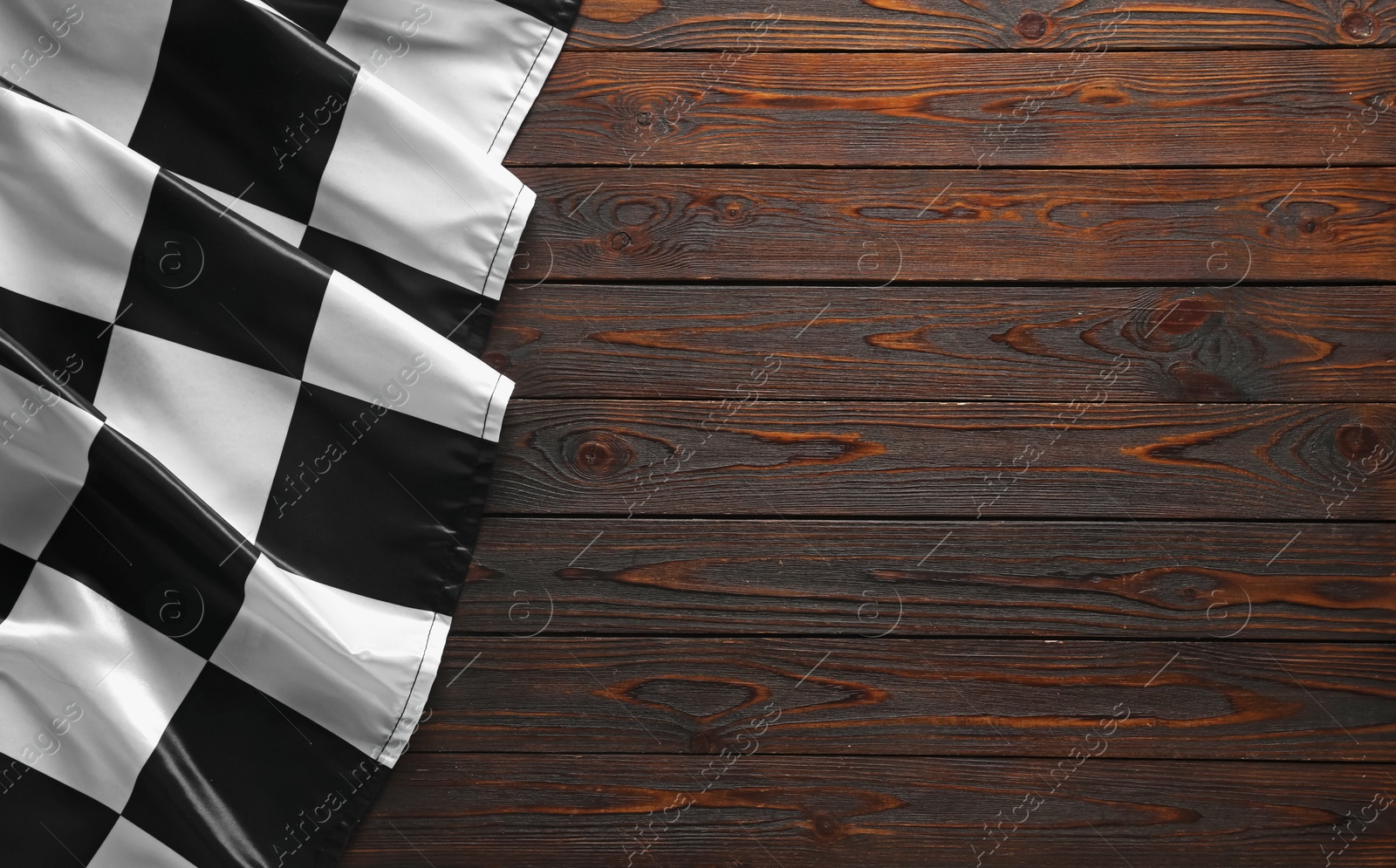 Photo of Checkered flag on wooden table, top view. Space for text