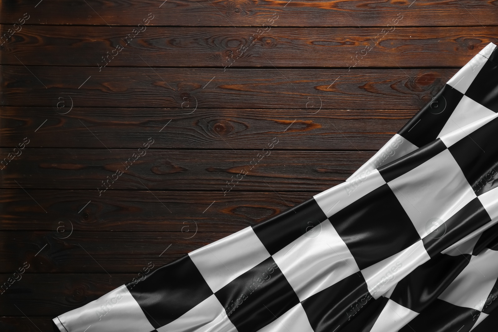 Photo of Checkered flag on wooden table, top view. Space for text