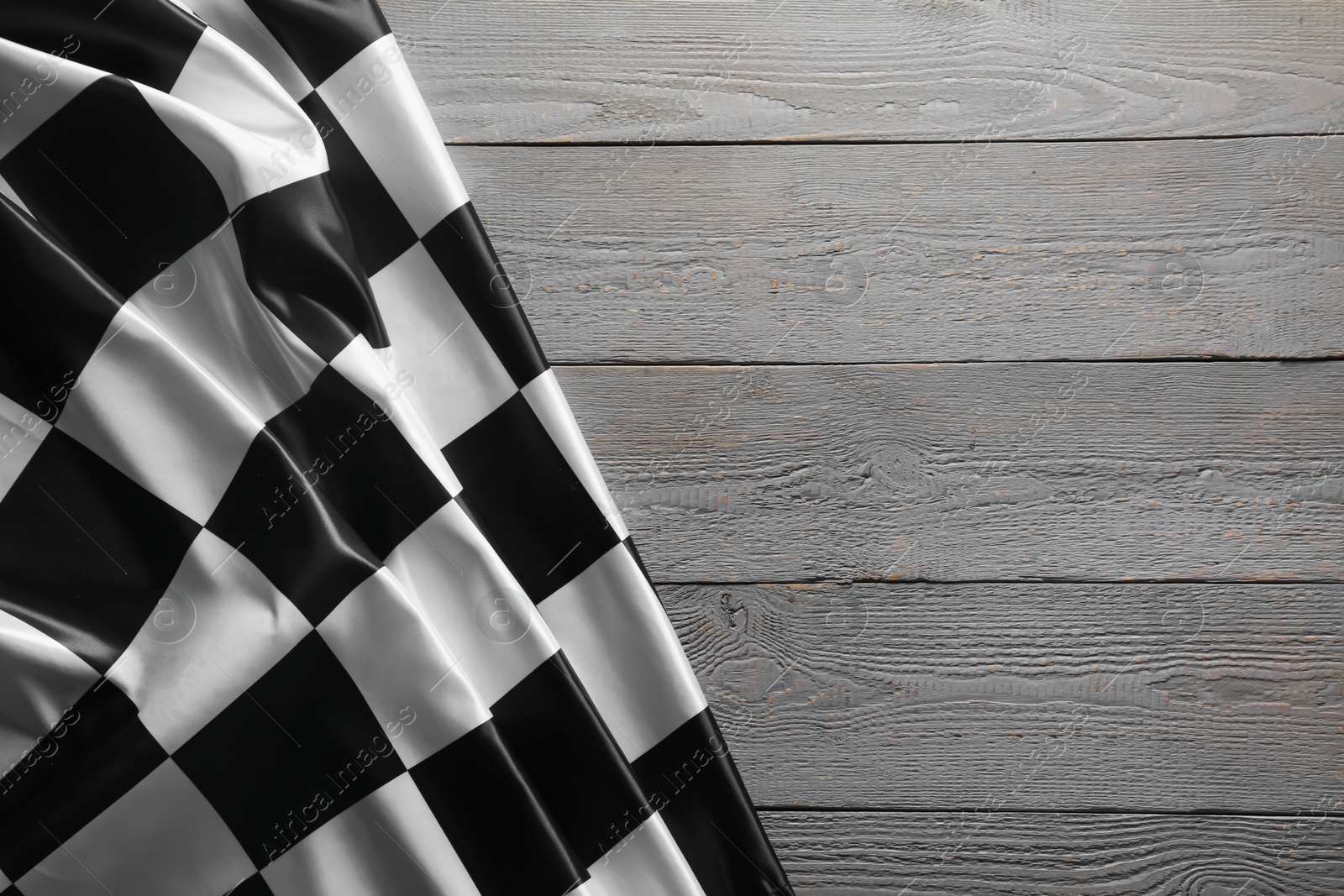 Photo of Checkered flag on grey wooden table, top view. Space for text