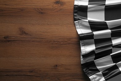 Photo of Checkered flag on wooden table, top view. Space for text