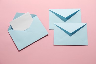 Photo of Paper envelopes with letter on pink background, flat lay. Mockup for design