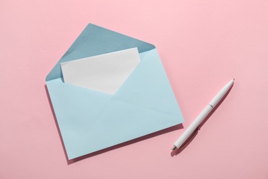 Photo of Paper envelope with letter and pen on pink background, top view. Mockup for design