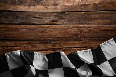 Photo of Checkered flag on wooden table, top view. Space for text