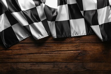 Photo of Checkered flag on wooden table, top view. Space for text