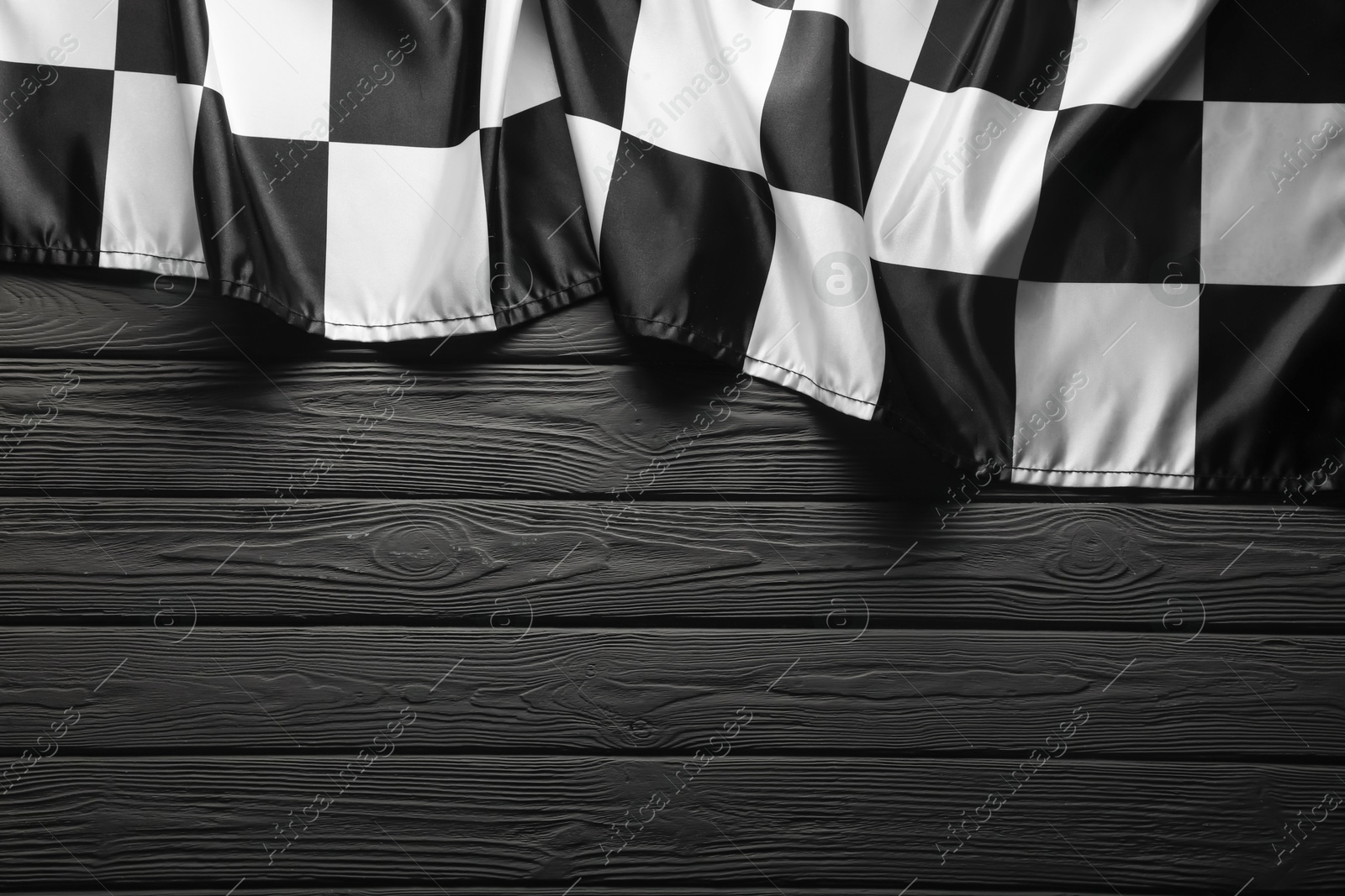 Photo of Checkered flag on black wooden table, top view. Space for text