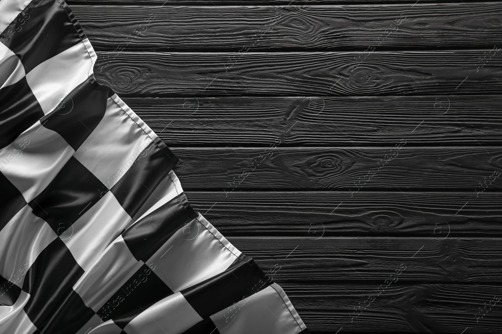 Photo of Checkered flag on black wooden table, top view. Space for text