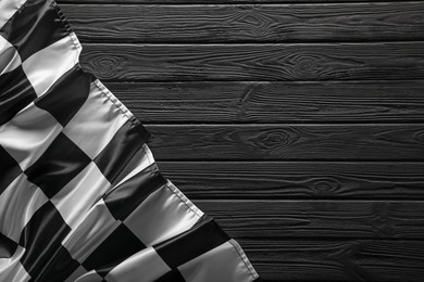 Photo of Checkered flag on black wooden table, top view. Space for text