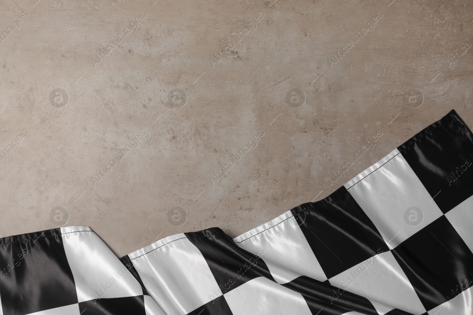 Photo of Checkered flag on grey table, top view. Space for text